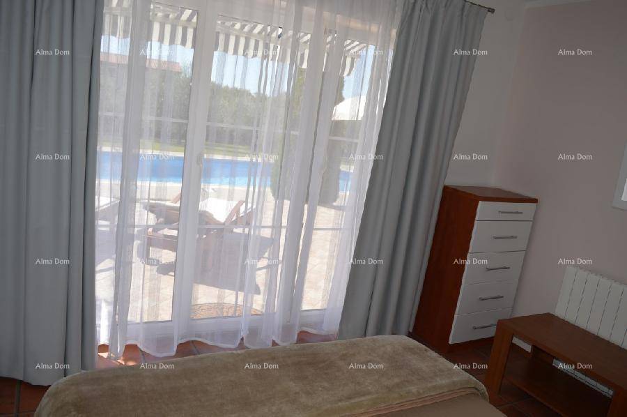 Schlafzimmer mit Blick auf den Poolbereich durch große Fenster, ausgestattet mit Vorhängen.