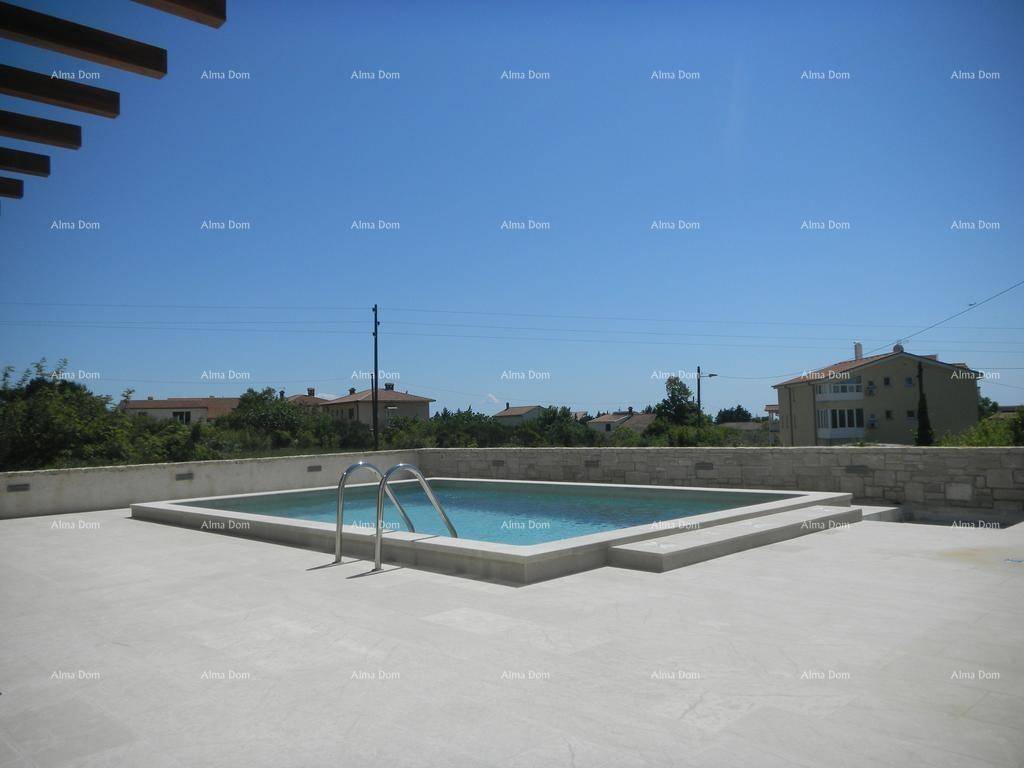 Außenpool mit klarem Wasser und gepflasterter Sonnenterrasse unter blauem Himmel.