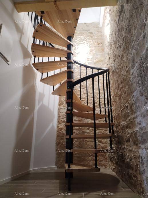 Elegante Wendeltreppe aus Holz und Metall, die verschiedene Ebenen des Hauses mit Steinwänden verbindet.