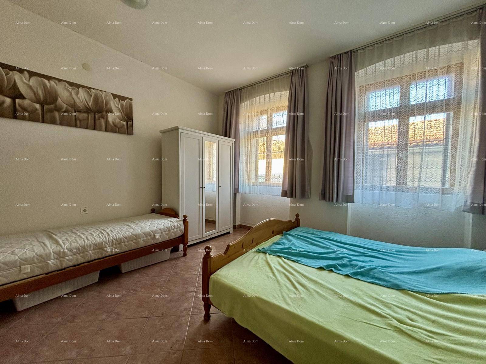 Geräumiges Schlafzimmer mit zwei Einzelbetten, einem Kleiderschrank und zwei Fenstern für viel Licht.