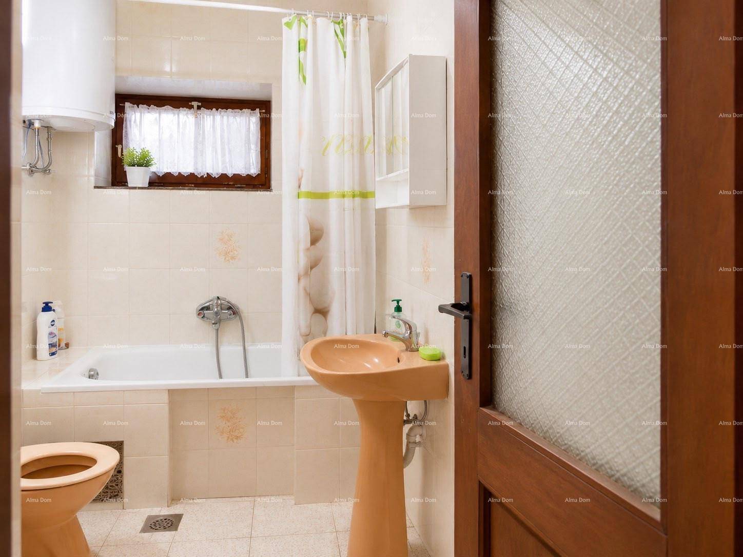 Helles Badezimmer mit Badewanne, Waschbecken und WC in beigen Fliesen.