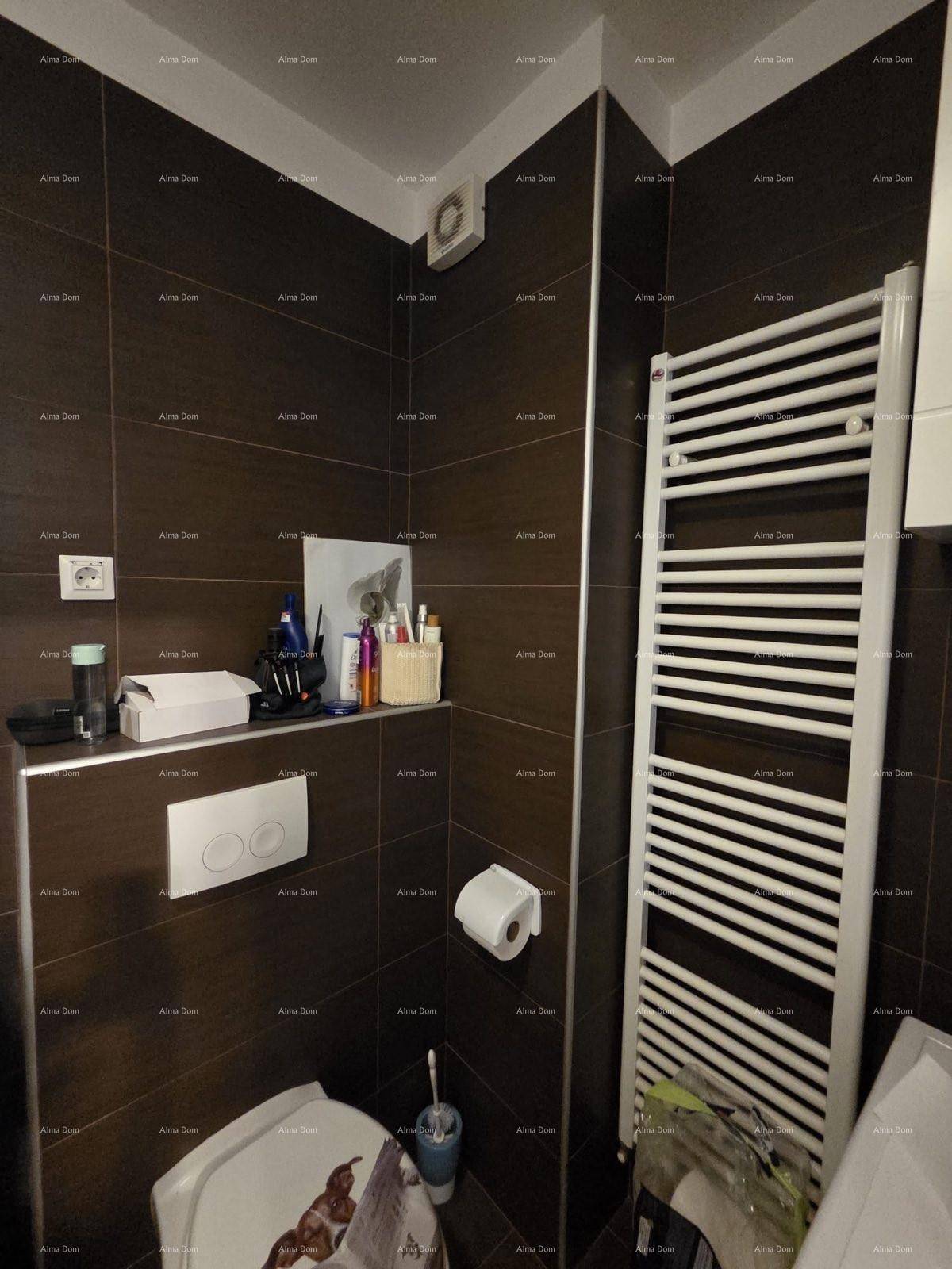 Badezimmer mit dunklen Fliesen, wandhängendem WC und einem beheizten Handtuchhalter.