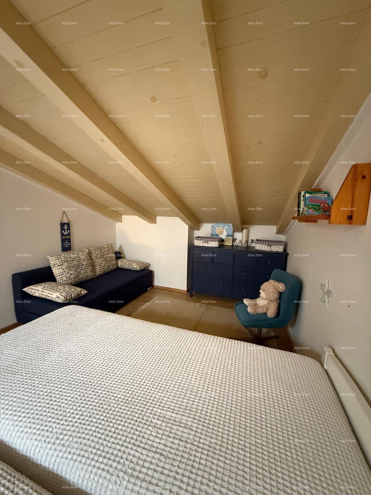 Gemütliches Schlafzimmer im Dachgeschoss mit Holzbalkendecke und schrägen Wänden.