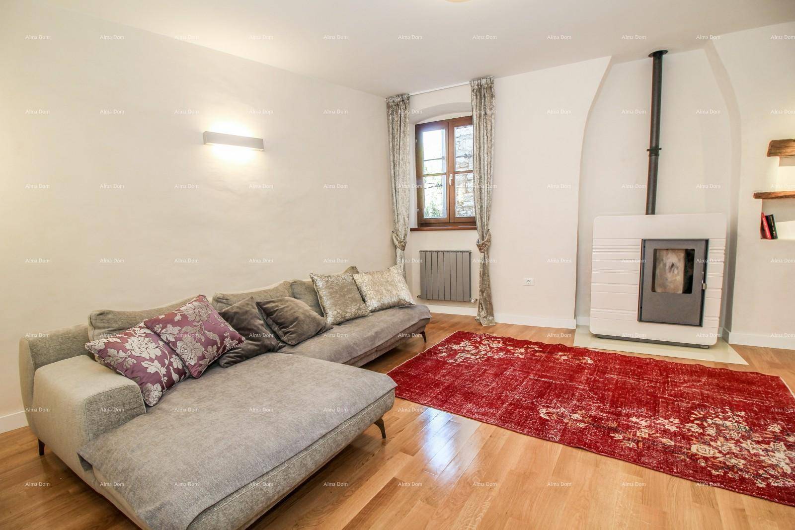 Heller Wohnbereich mit bequemer Couch, Holzboden und einem dekorativen roten Teppich.