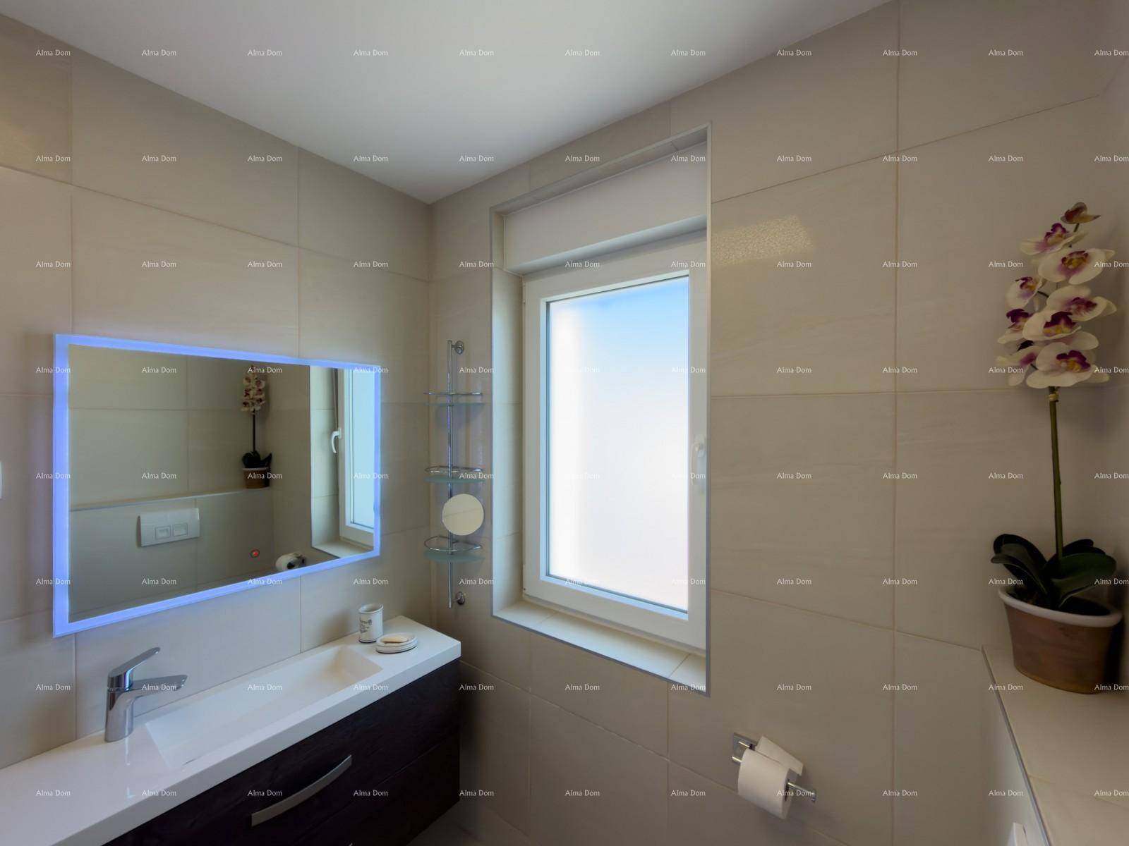Modernes Badezimmer mit beleuchtetem Spiegel, Waschtisch und Fenster für natürliche Belichtung.