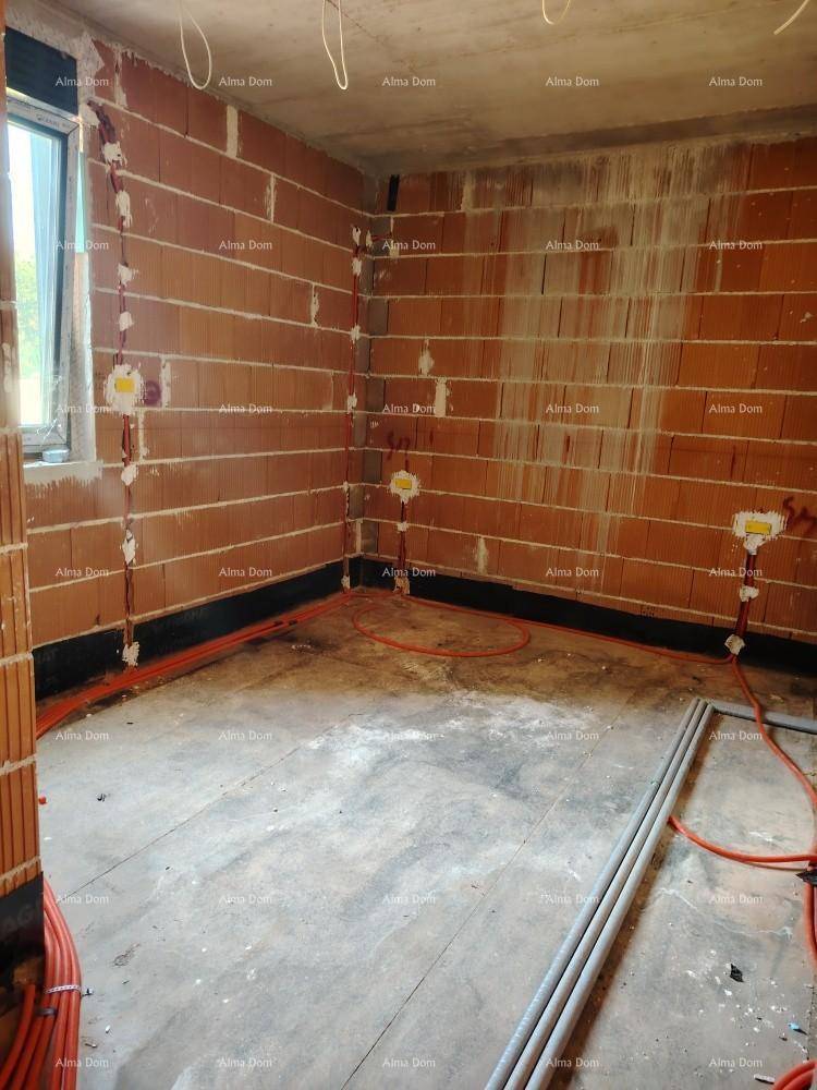 Innenraum im Rohbau mit Ziegelwänden, Betonboden und sichtbaren Elektroinstallationen und einem Fenster.