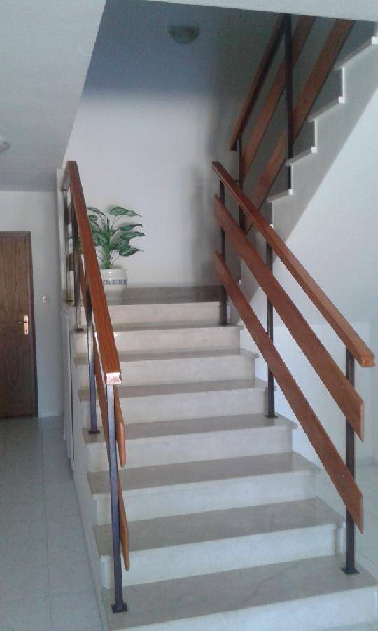 Detailansicht der Treppe im Flur mit Holzgeländer und hellen Stufen, die nach oben führen. 
