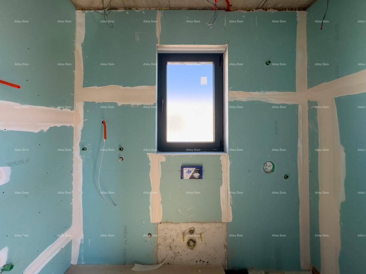 Badezimmer im Rohbau mit blauen Trockenbauwänden, Fenster und vorbereiteten Anschlüssen für die Sanitäreinrichtung.
