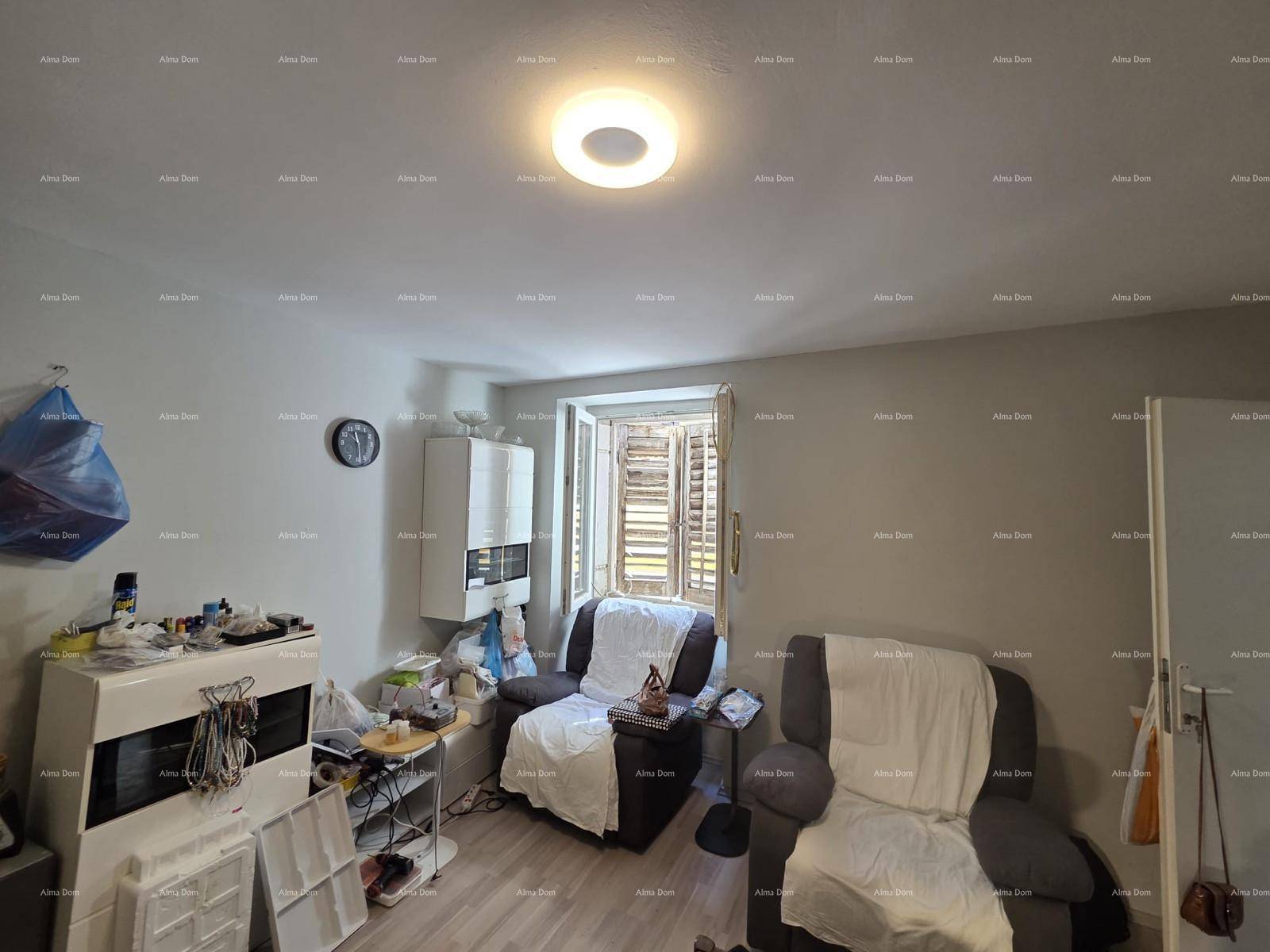 Gemütliches Wohnzimmer mit zwei Sesseln, Laminatboden und einem Fenster mit Holzläden.