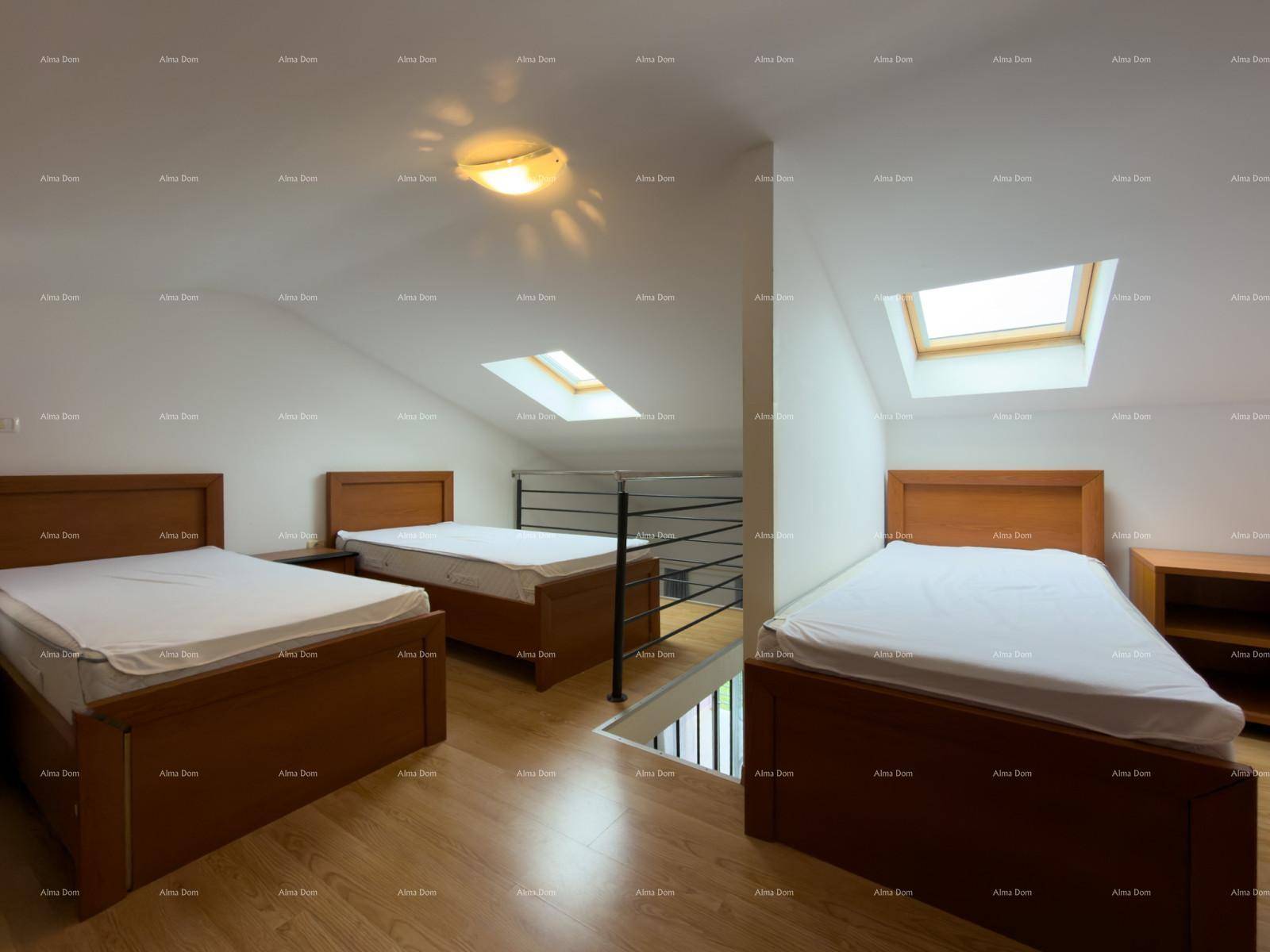 Helles Dachgeschoss-Schlafzimmer mit drei Betten, Holzfußboden und viel Tageslicht durch Dachfenster.