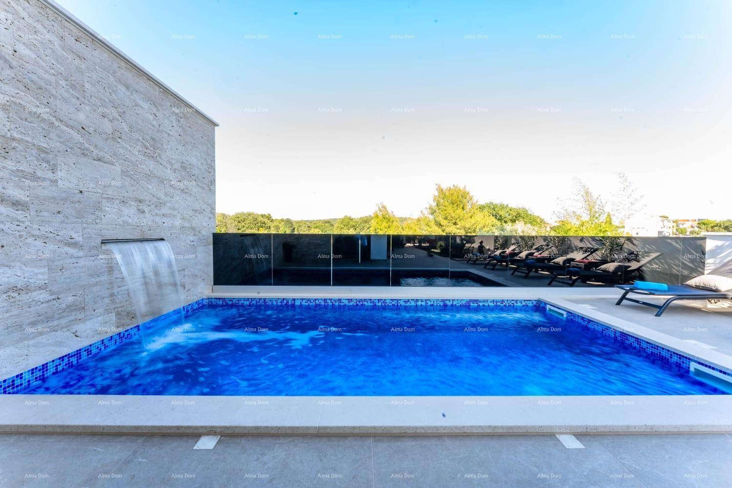Großer Außenpool mit blauen Mosaikfliesen und einem dekorativen Wasserfall an der Steinwand.