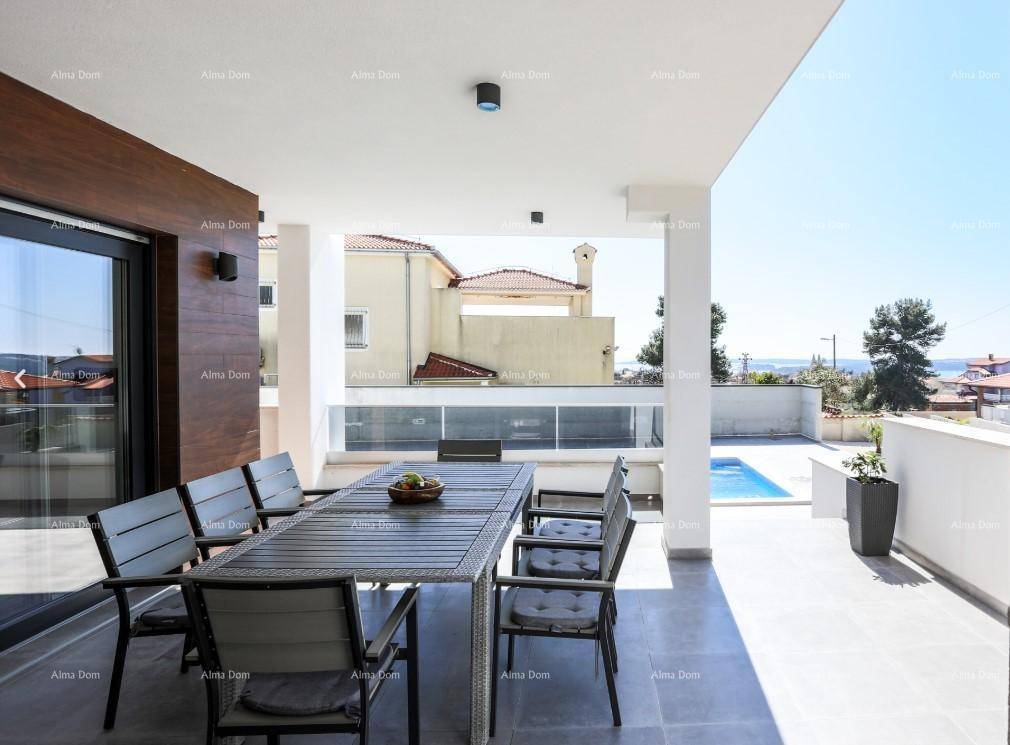 Überdachte Terrasse mit Esstisch und Stühlen, Blick auf den Pool und das Meer in der Ferne.