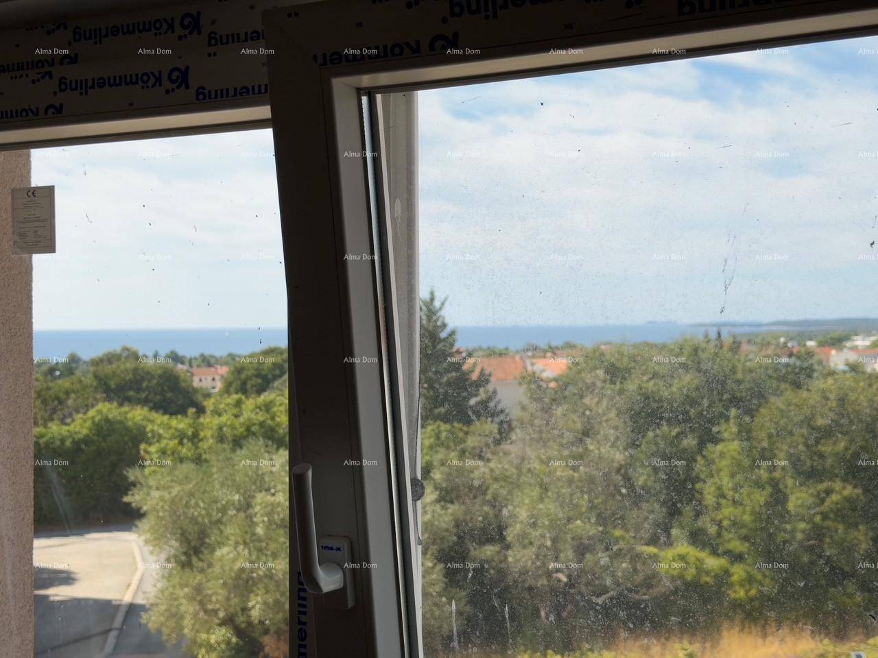 Fensterblick auf das Meer und die grüne Umgebung mit Häusern in der Ferne.
