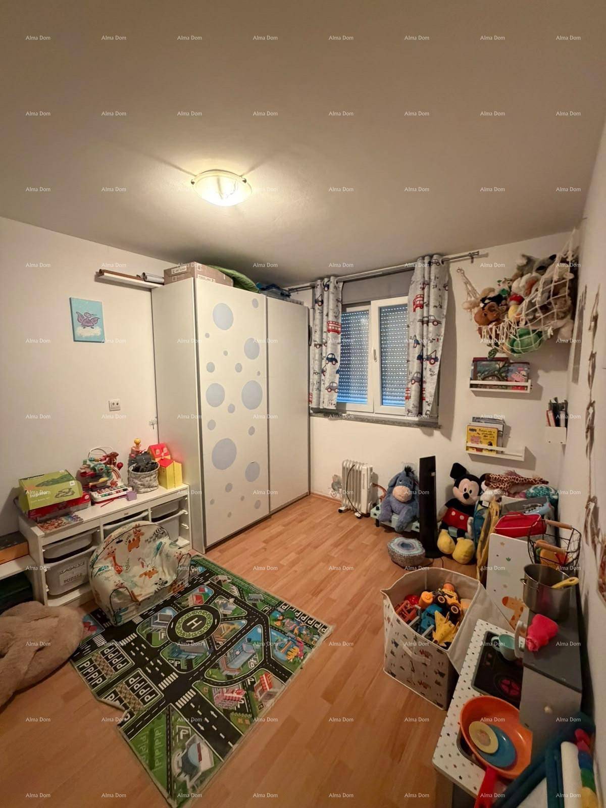 Kinderzimmer mit Holzboden, Fenster und viel Stauraum für Spielzeug.