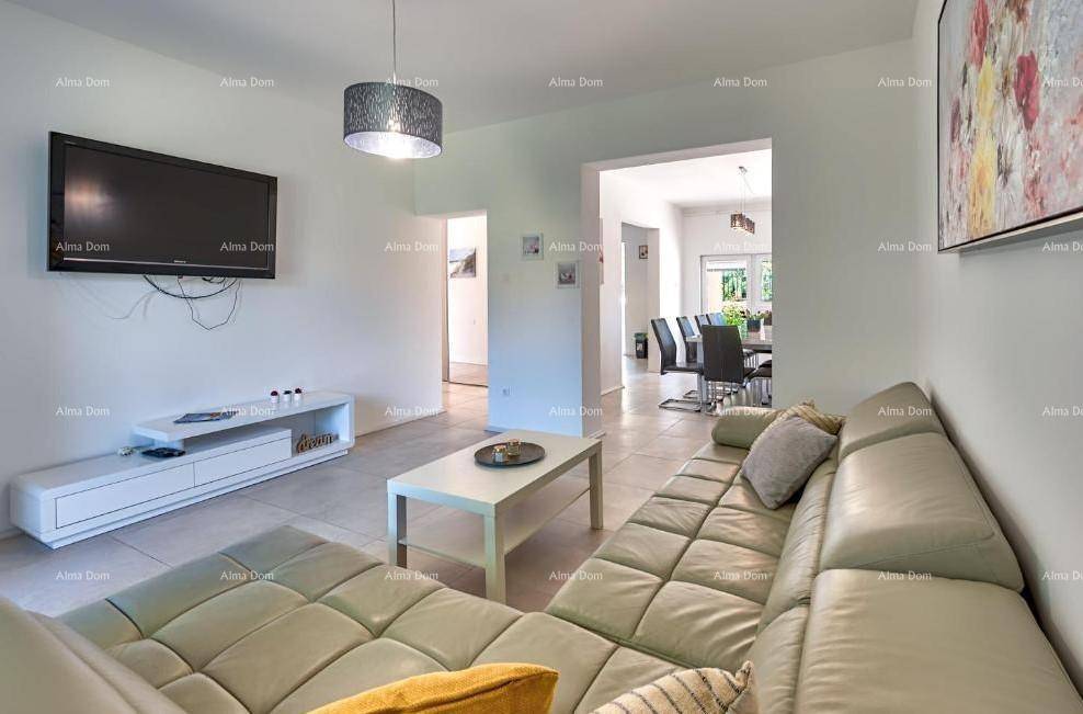 Gemütliches Wohnzimmer mit Sofa und Fernseher, offen zum Essbereich.