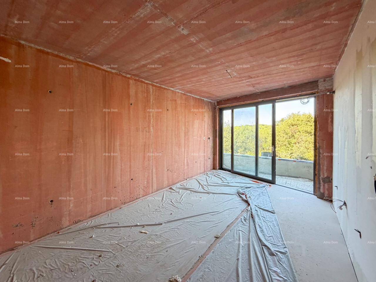 Geräumiger Raum im Rohbau mit großen Fenstern und Zugang zu einem Balkon.