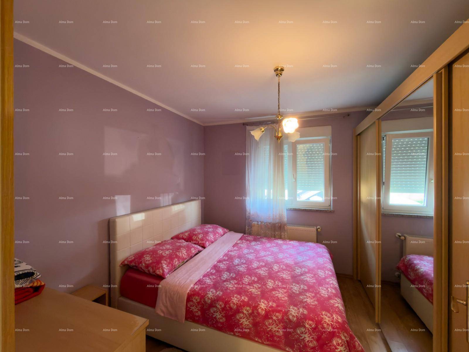 Schlafzimmer mit Doppelbett, rosa Bettwäsche und Kleiderschrank mit Spiegeltüren.