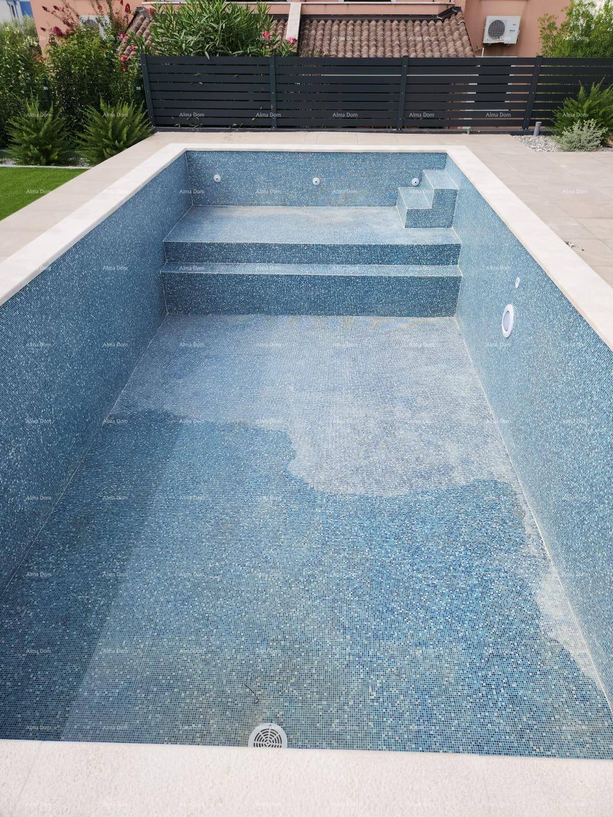 Leeres Schwimmbecken mit blauen Mosaikfliesen und integrierten Stufen, umgeben von hellen Fliesen.