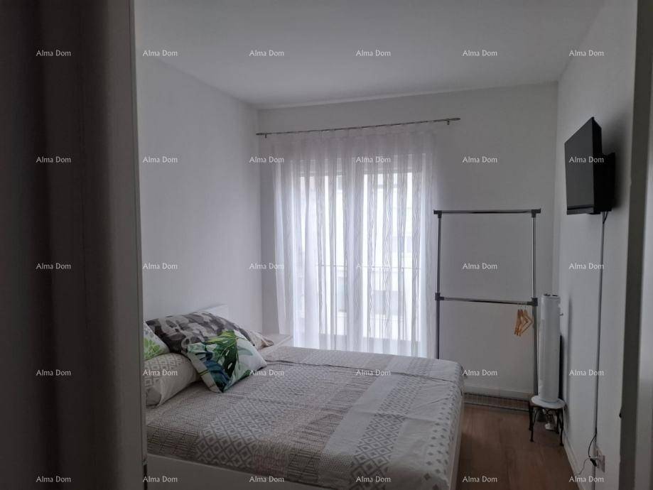 Schlafzimmer mit Doppelbett, großen Fenstern und einem Kleiderständer.