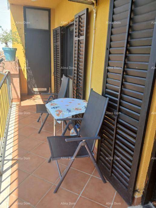 Sonniger Balkon mit Tisch und Stühlen, umgeben von Fensterläden und einer gelben Fassade.