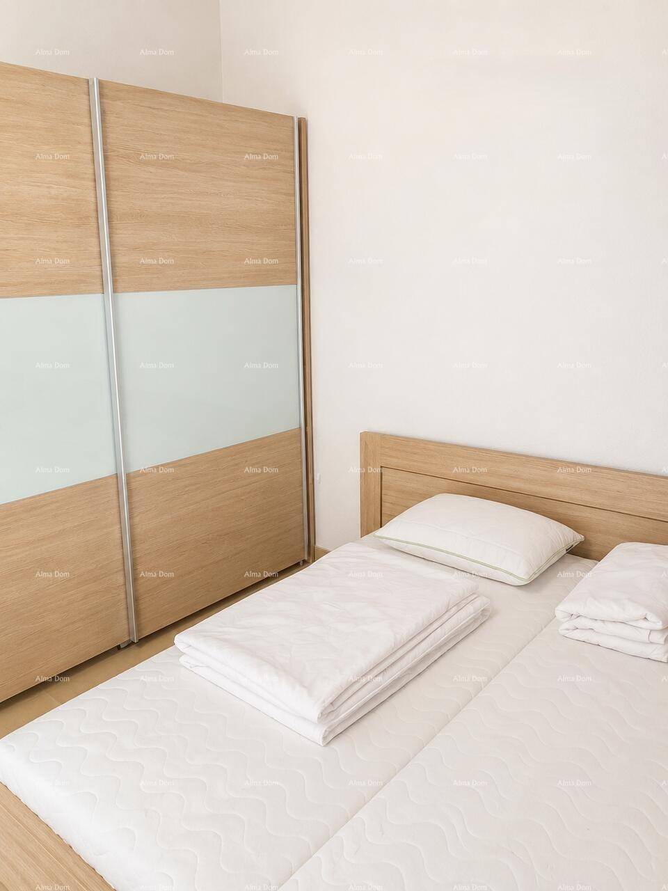 Schlafzimmer mit Doppelbett, hellem Holzrahmen und großem Schiebetürenschrank, bietet viel Stauraum.