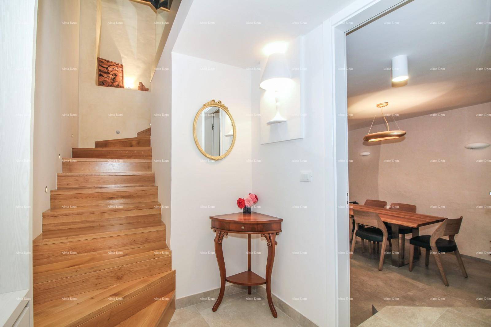 Heller Eingangsbereich mit eleganter Holztreppe, einem runden Spiegel und Zugang zum Essbereich.