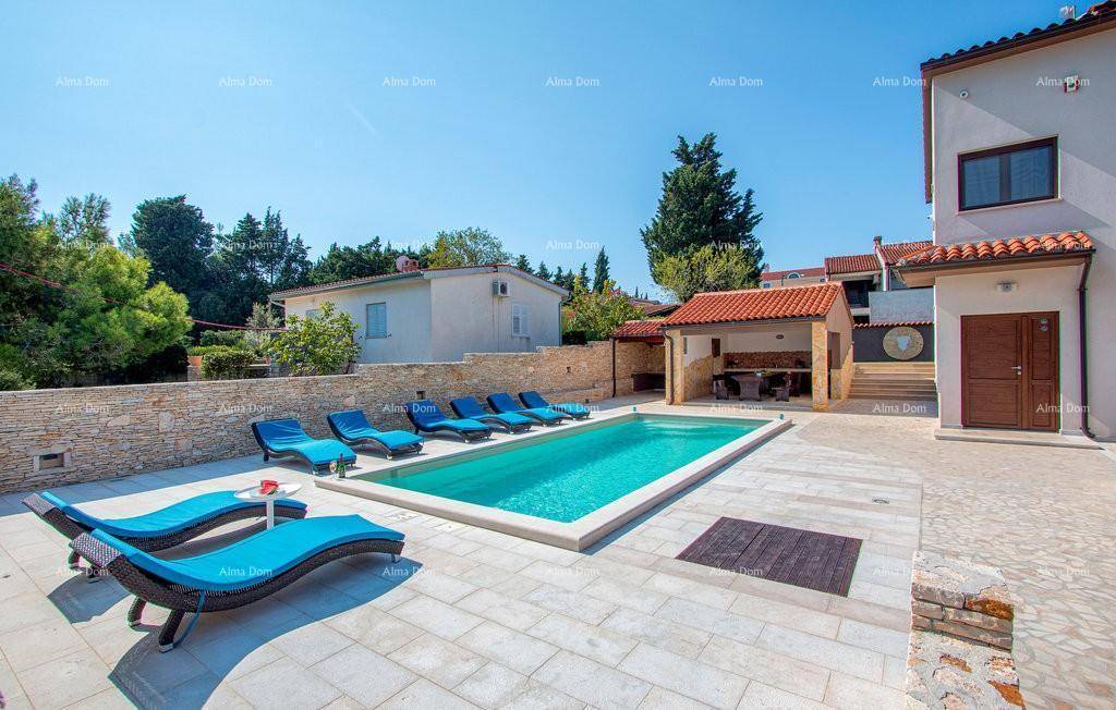 Weitläufiger Poolbereich mit Liegestühlen und Blick auf das moderne Wohnhaus.