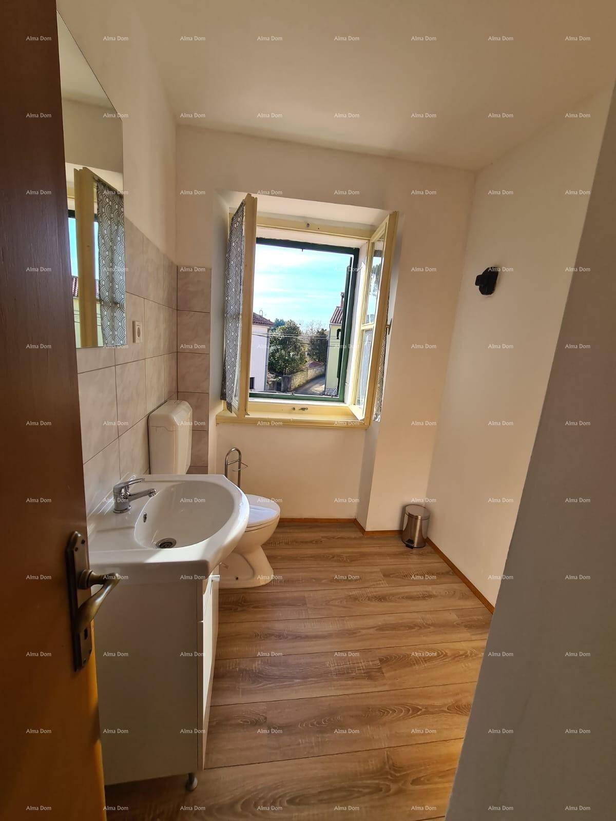 Badezimmer mit Waschbecken, Toilette und einem Fenster, das viel Tageslicht hereinlässt und Ausblick bietet.