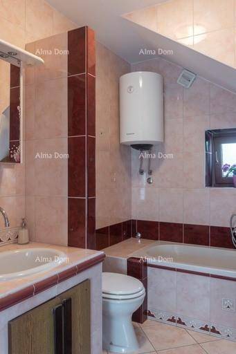 Badezimmer mit Badewanne, WC und Waschbecken unter Dachschräge, gefliest in warmen Farbtönen.