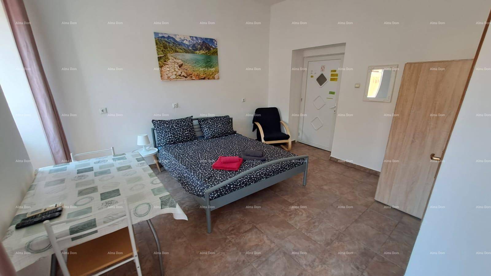 Studio-Apartment mit Schlafbereich, Esstisch und Kunst an der Wand, funktional und hell eingerichtet.