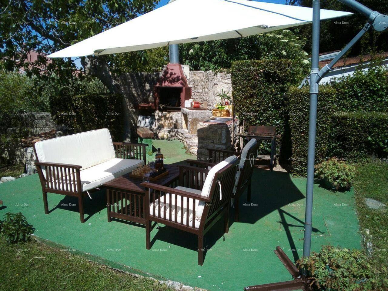 Gemütlicher Sitzbereich im Garten mit Sonnenschirm, Holzmöbeln und gemauertem Grillplatz.