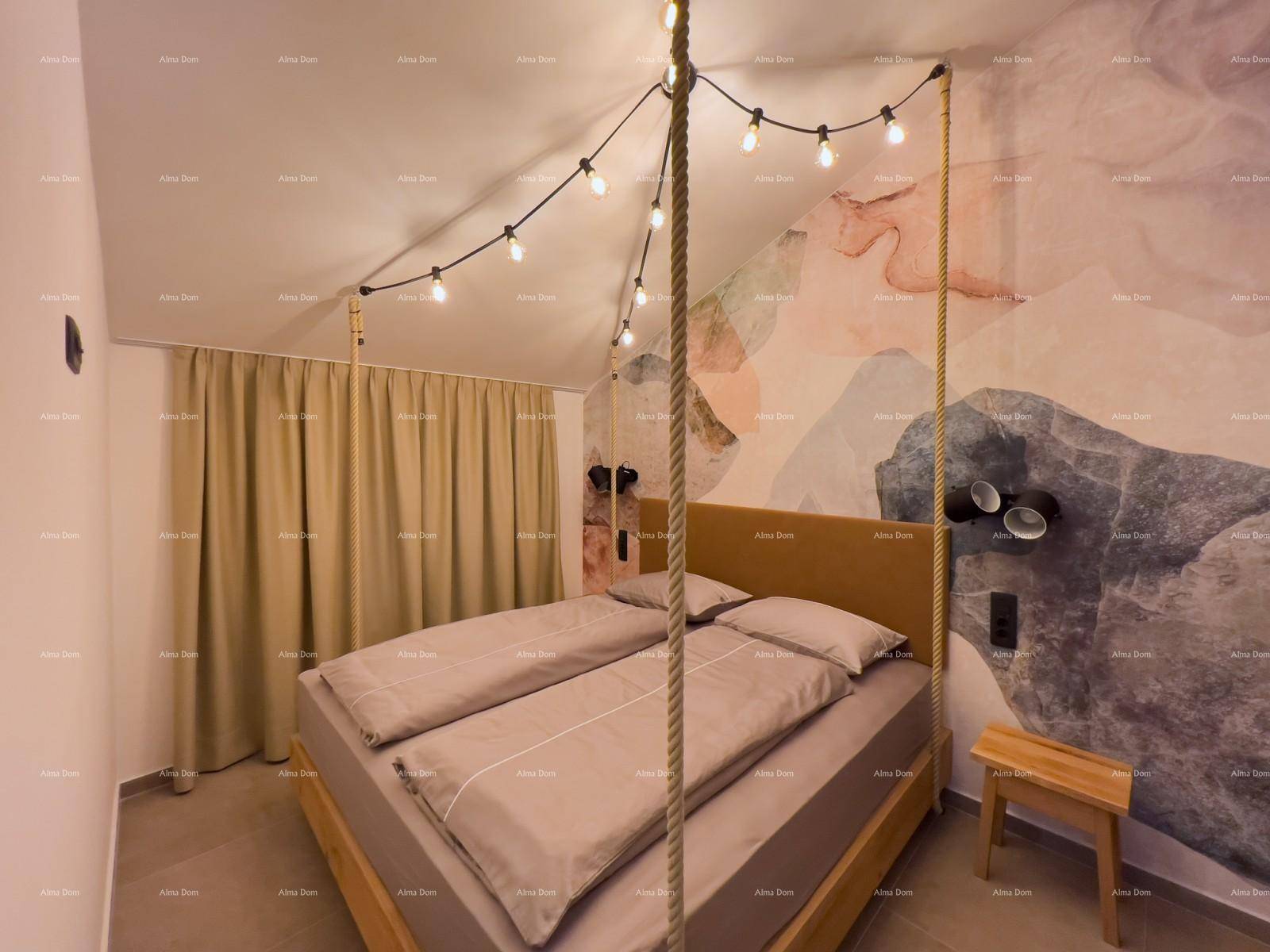 Schlafzimmer mit Doppelbett, farbiger Wandgestaltung und Lichterkette als Deckenbeleuchtung im Dachgeschoss.