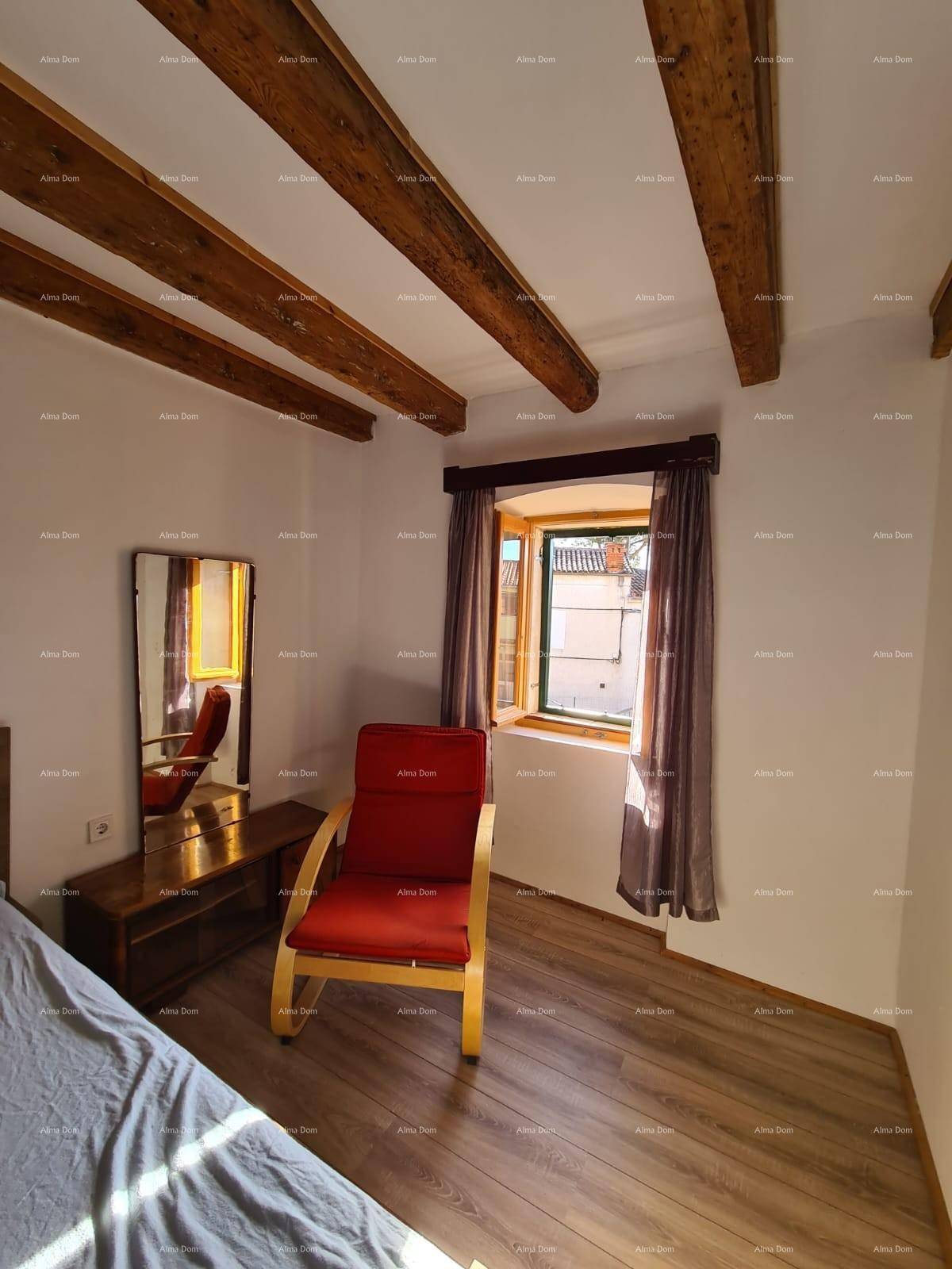 Gemütliches Schlafzimmer mit Holzbalkendecke, Holzboden und einem Fenster mit Blick ins Grüne.