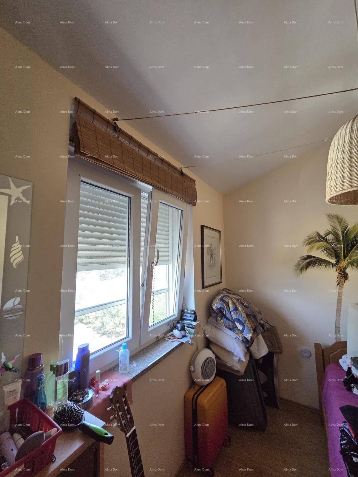 Schlafzimmer mit Fenster, schrägen Decken und dekorativer Palme, bietet eine gemütliche Atmosphäre.