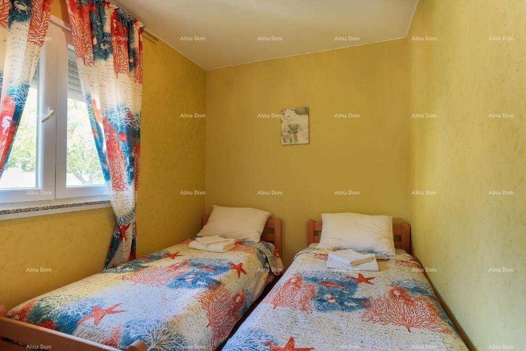 Kleines Schlafzimmer mit zwei Einzelbetten, Holzboden und farbenfrohen Vorhängen.