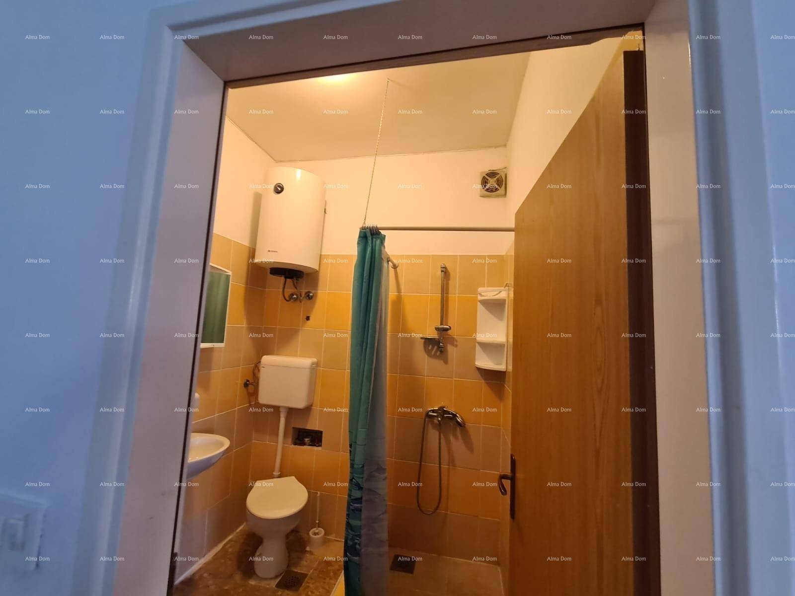 Badezimmer mit Toilette, Waschbecken und Duschbereich, ausgestattet mit gelben Fliesen.