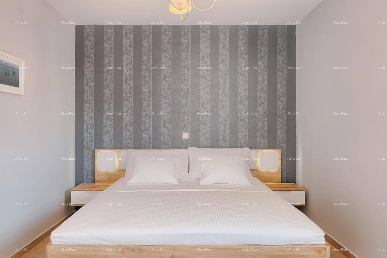 Schlafzimmer mit Doppelbett, gestreifter Akzentwand und beleuchteten Nachttischen.