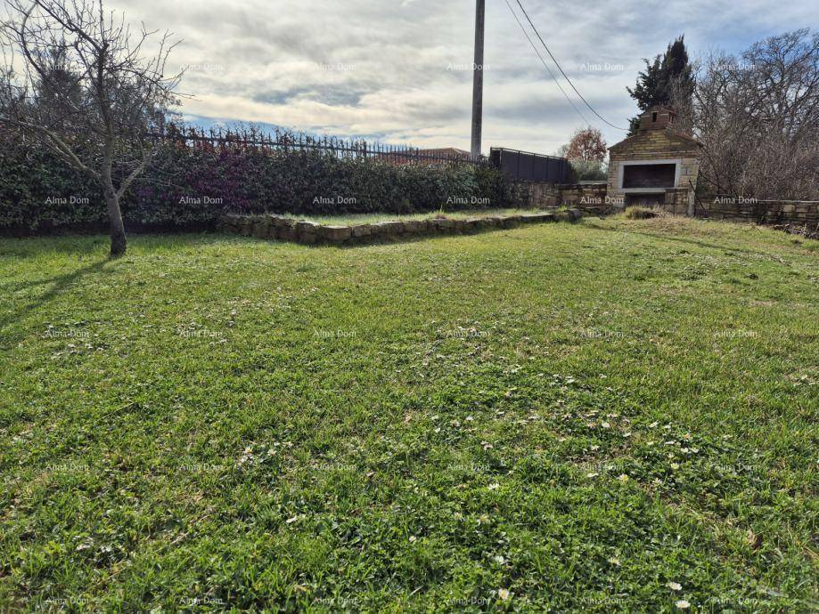 Weitläufiger Garten mit Rasenfläche und einem gemauerten Grillplatz im Hintergrund.