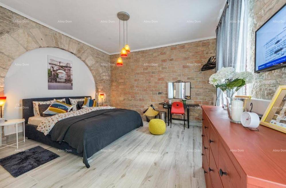 Geräumiges Schlafzimmer mit freigelegter Ziegelwand, Holzboden und einem Schreibtischbereich.
