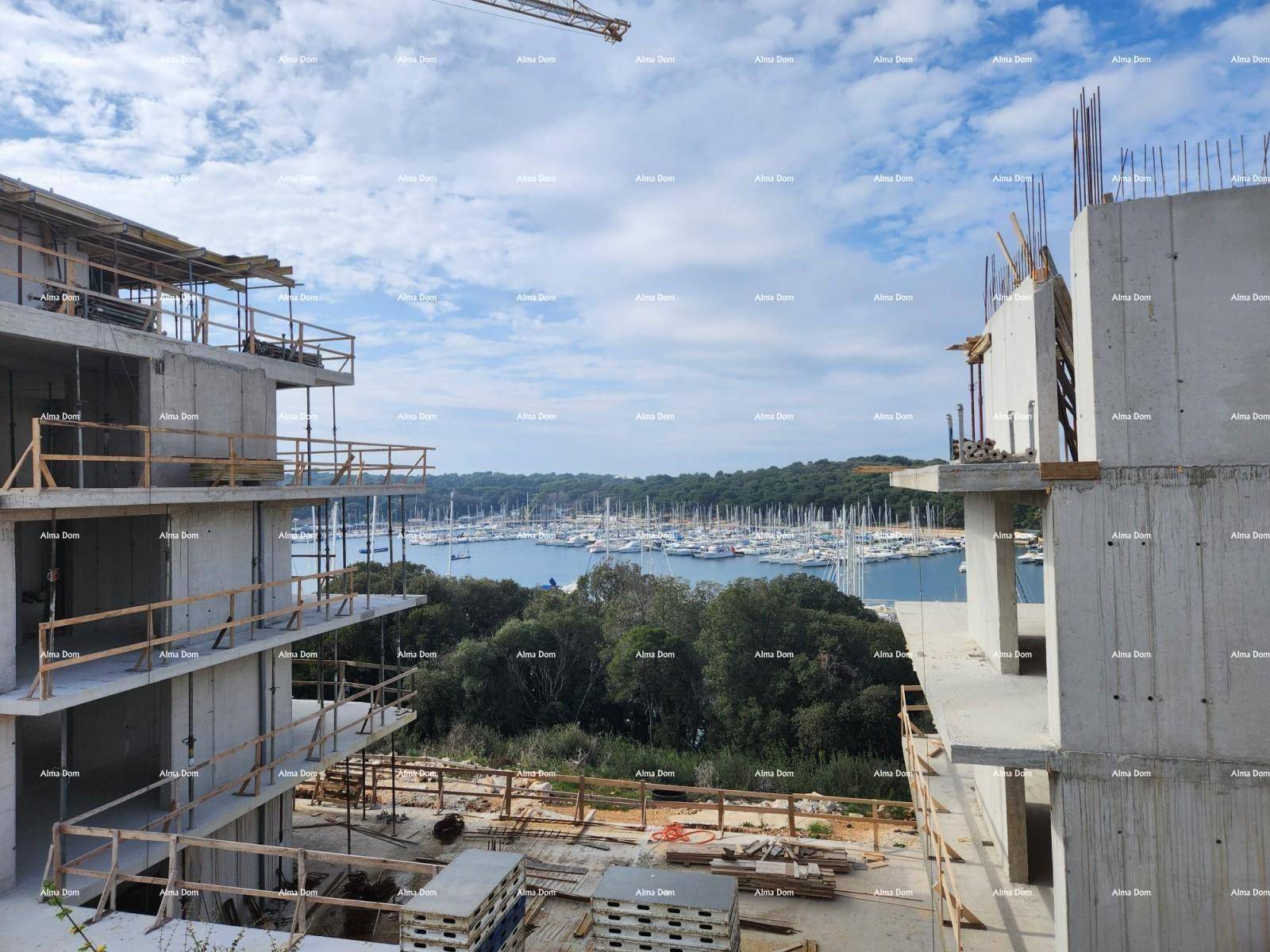 Blick zwischen zwei im Bau befindlichen Gebäuden auf den Yachthafen und das Meer.