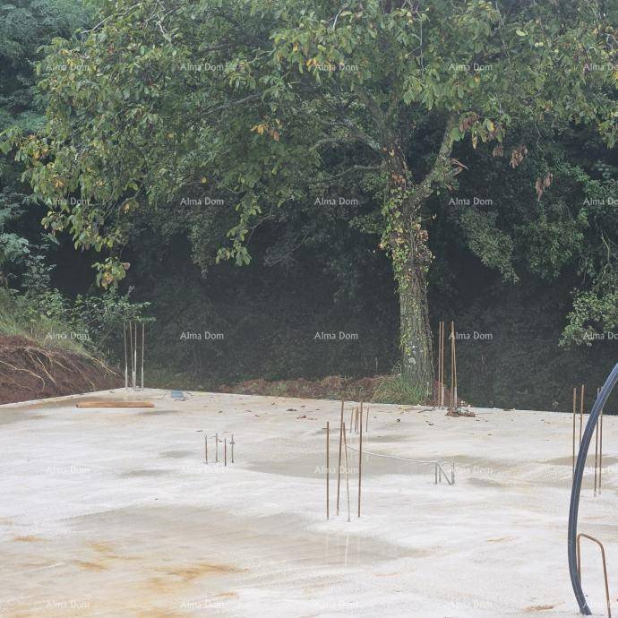 Betonfundamentplatte einer Baustelle mit Bewehrungsstäben und einem großen Baum im Hintergrund.