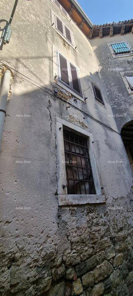 Altes Gebäude mit Steinfundament und verputzten Wänden, zeigt Fenster mit Fensterläden und Gitter.