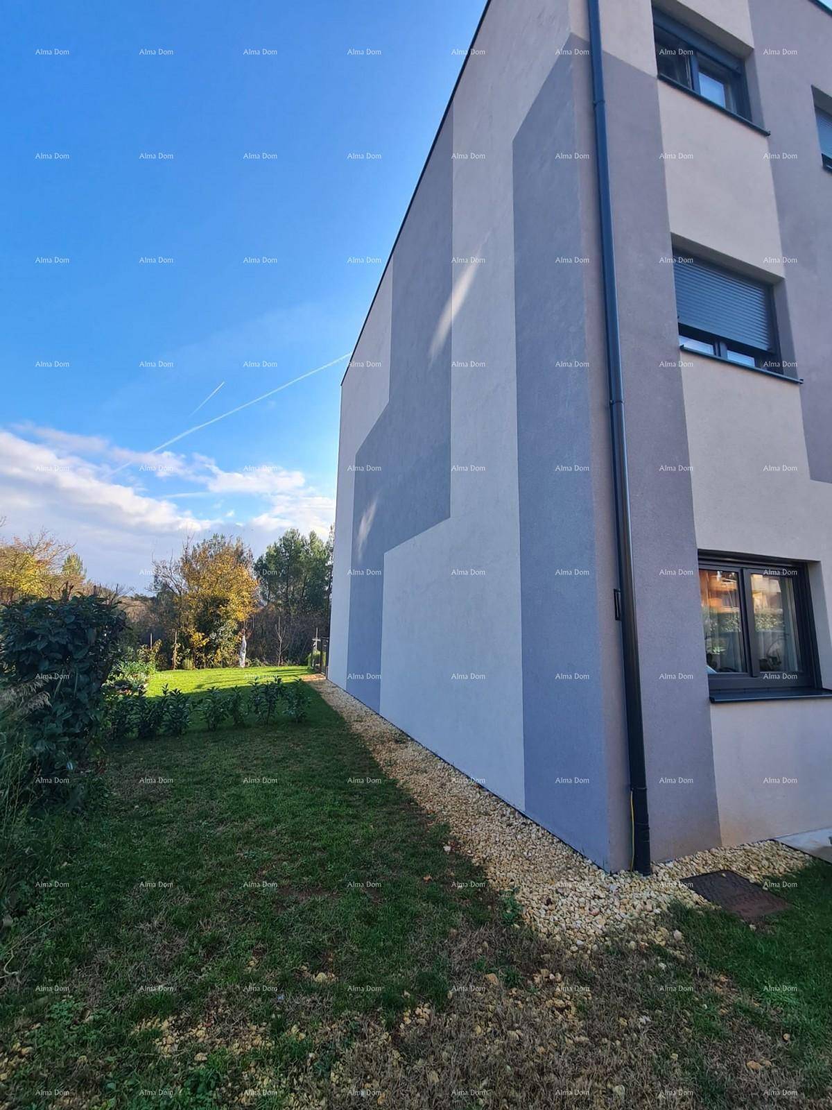Seitenansicht eines modernen Gebäudes mit grauer Fassade und angrenzender Grünfläche.