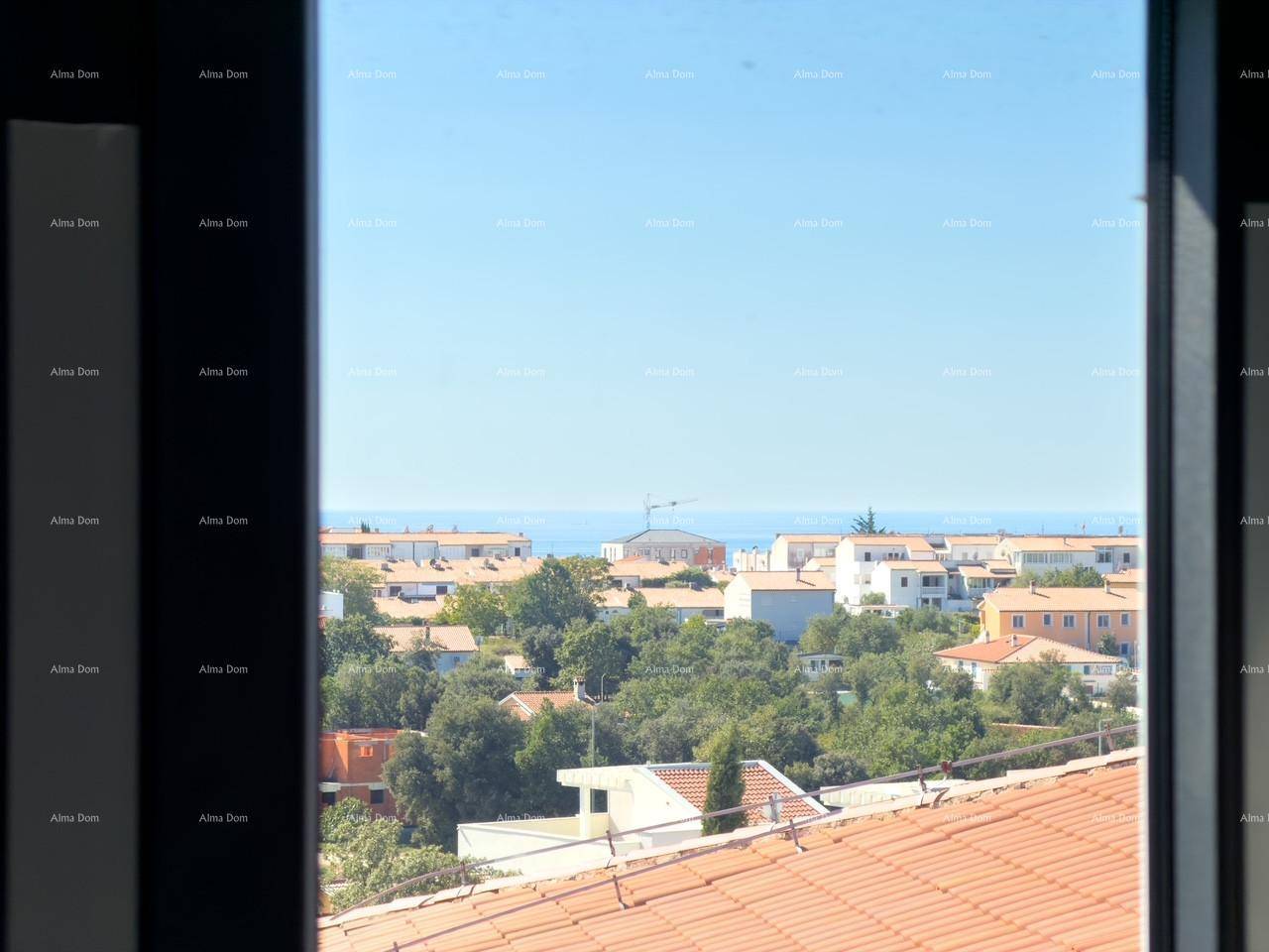 Blick aus dem Fenster auf die Dächer der Häuser, grüne Bäume und das ferne Meer.