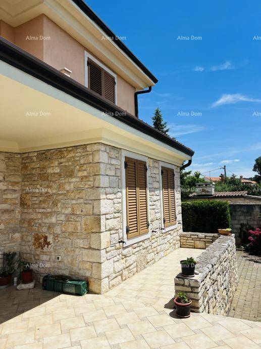 Seitenansicht des Hauses mit traditioneller Steinfassade, Holzfensterläden und einem gefliesten Außenbereich.