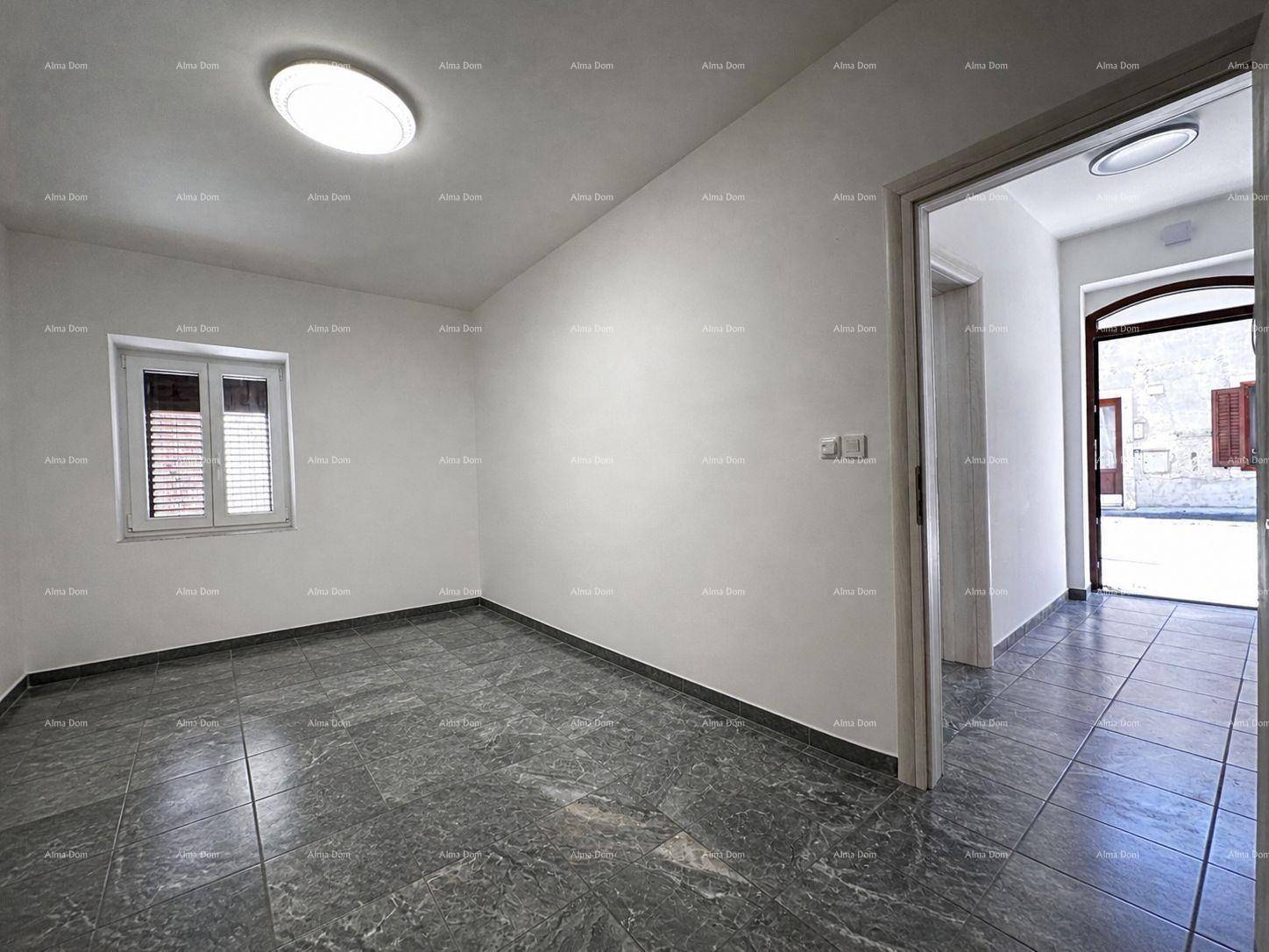 Heller, leerer Raum mit Fliesenboden und Zugang zu einem weiteren Bereich, ideal für Wohnzwecke.