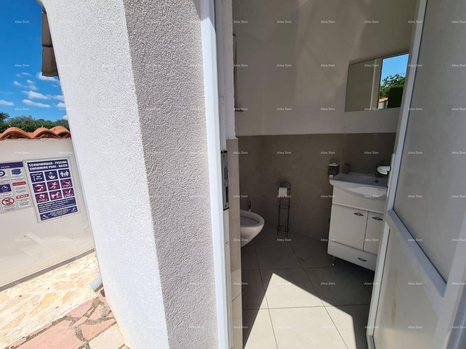 Kleines WC mit Waschbecken und Toilette, zugänglich von einem Außenbereich.