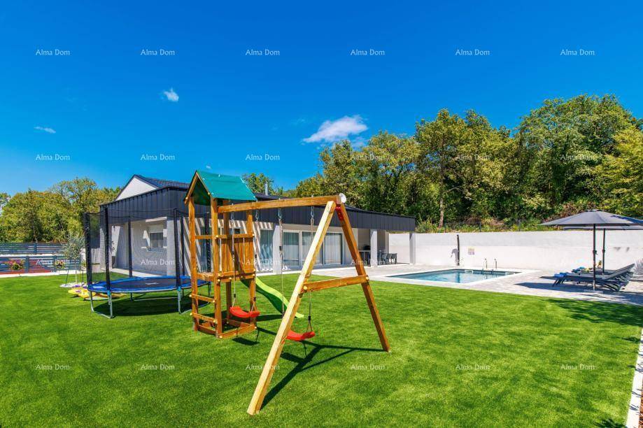 Großer Garten mit Kinderspielplatz, Trampolin und Rasenfläche neben dem modernen Haus.