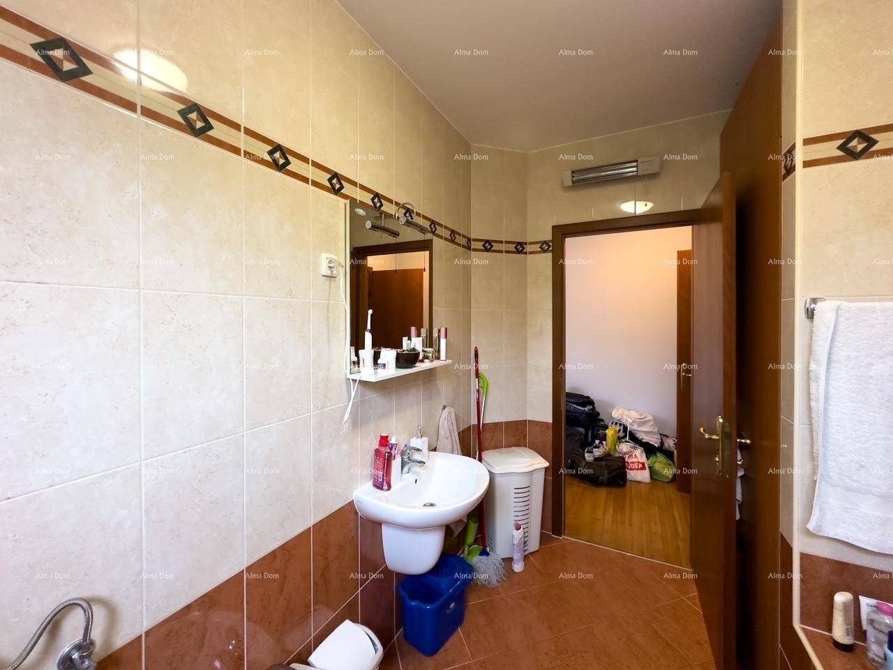 Gefliestes Badezimmer mit Waschbecken, Spiegel und Zugang zu einem angrenzenden Raum, funktional gestaltet.