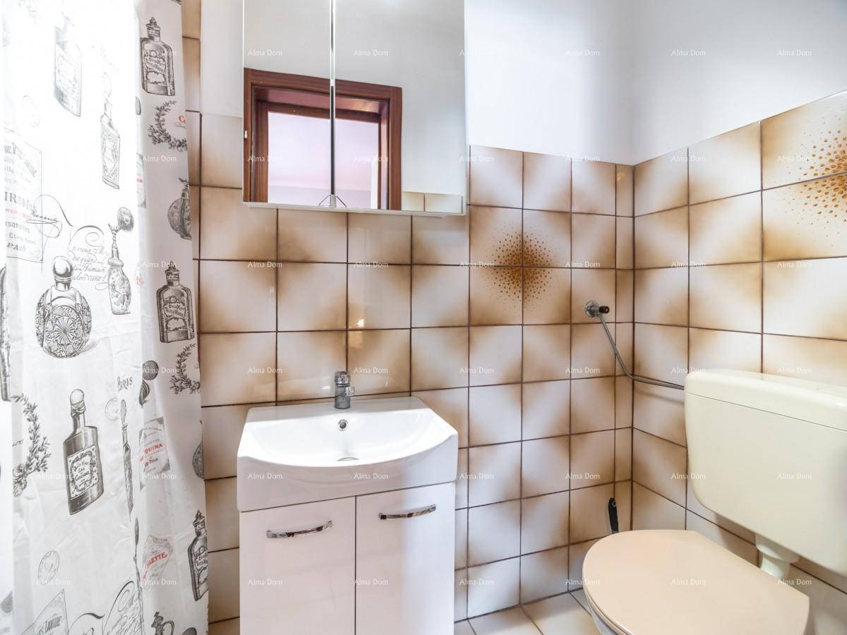 Badezimmer mit beigefarbenen Fliesen, WC, Waschbecken und Duschvorhang.